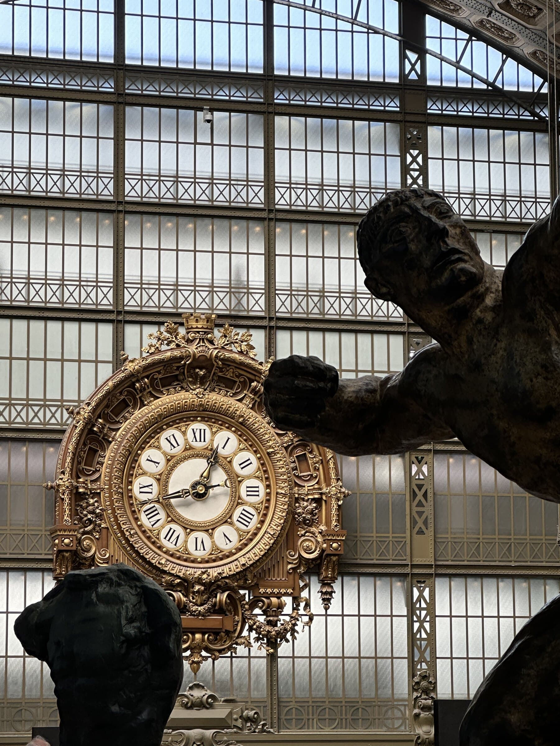 Paris clock and sculpture detail inside a grand hall.